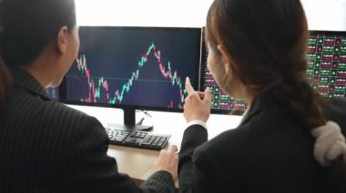Hisse senedi ticareti şirketindeki yavaş hareket eden yatırımcılar, monitörlerde sergilenen borsa pazarlamasında kâr elde ettikten sonra heyecanlanıp kutlama yapıyorlar. Filizlenen