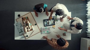 Mimar mühendis ekibinin tartıştığı ve tablet görüntüleme inşaatını planlı ve ev modeliyle toplantı masasında işaret ettiği en tepeden aşağı bakış açısı. Çeşitli tasarımcı tasarım evleri. Hizalama.