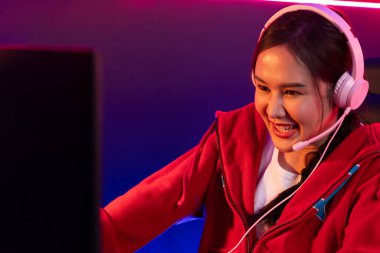Portre sunucusu güzel Asyalı kız flamasının çevrimiçi oyun oynaması kulaklık takması pastel renkli konuşmalar izleyici medyası ile çevrimiçi. Esport yetenekli takım oyuncuları neon mavi odada. Taktik.