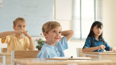 Sınıfta okuyan çeşitli çocuklarla çevrili beyaz bir çocuk öğretmenine soru sorup cevap verdiği için elini kaldırıyor. Mutlu öğrenci birlikte çalışıyor, oy veriyor, gönüllü oluyor, hocayı arıyor. Pedagoji.