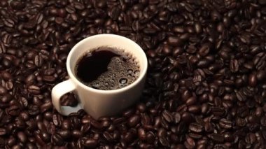 Kahve ya da kahve çekirdekli espresso manzarası. Taze kavrulmuş kahve çekirdeğini yakın çekimde ahşap masanın etrafına bir fincan americano ve aromatik akarsu ve tohum dumanı serpin. Geliştirilebilir.