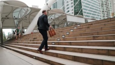 Kafkasyalı zeki işadamı şehir manzarası ile çevrili merdivenleri çıkıyor. Hırslı proje yöneticisinin modern inşaatta zorlu bir iş ya da yatırım fırsatı bulması. Urbane.