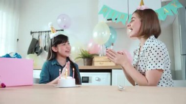 Enerjik kız ve anne birlikte müzik eşliğinde doğum günü şarkısı söylüyorlar. Kafkasyalı anne doğum gününü yemek odasında renkli balonla süslenmiş pastayla kutladı. Pedagoji.