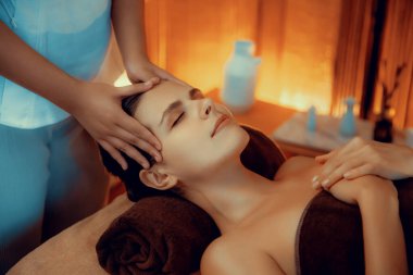 Beyaz kadın stres önleyici kafa masajı yapmaktan ve lüks otel veya otelde sıcak mum ışığında yüz güzelliği eğlencesi yapmaktan zevk alıyor. Sessiz.