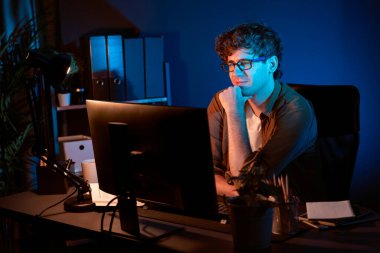 Genç işadamı, Neon Light Modern Ofis 'te yaratıcı bir başlangıç projesi için bilgisayara odaklanıyor. Düşünüyorum da, pazarlama ağı yaratıcıdan pazar kanalı tasarım konseptine çevrimiçi planlama. Toplayıcı.