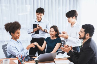 Çeşitli iş arkadaşları başarıyı şirket işyerindeki el sıkışma ve takım çalışmasıyla kutluyor. Çok kültürlü, mutlu profesyonellerden oluşan bir ekip ofiste tokalaşarak birlik oldular. Uyum