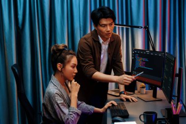 Bilgi teknolojisi geliştiricileri modern ofisteki neon ışık odasında verileri çevrimiçi olarak çalıştıran akıllı web sitesi geliştirme kodlayıcı sistemine işaret ediyorlar. İnfobahn.