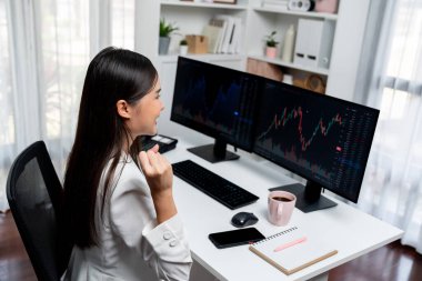 Başarılı genç Asyalı iş kadını, modern ofisteki bilgisayar ekranlarında dinamik iş grafiği üzerine borsada yumruklaşarak en yüksek karı elde ediyor, finansal teknolojiyi analiz ediyor. Taktik.