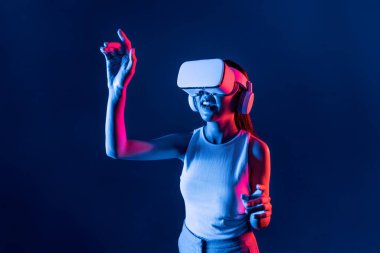 Siberpunk neon ışığı altında duran zeki kadın metaevrene bağlı VR kulaklık takıyor, gelecekçi siber uzay topluluğu teknolojisi. Zarif bir kadın parmak ucu kullanarak sanal bir obje oluşturur. Halüsinasyon.