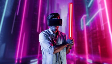 Lazer kılıcı tutan ve VR gözlük takan oyuncu. Beyaz adam, neon şatonun etrafında dikilirken görsel gerçeklik kulaklığı kullanıyor. Yenilik teknolojisi. Sapma.