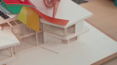 Mimari ekipman kullanarak yavaş çekim ev tasarımcısı bir plan çizerken, iç mimari tasarımcı da müşterilerin talebine göre renk örneklerinden uygun renkler seçiyor. Değiştirilmiş