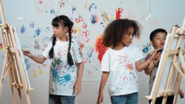 Çeşitli öğrenciler resim dersinde duvarları boyadı ya da resim çizdi. Lekeli duvarda el iziyle dururken beyaz gömlek giyen Asyalı bir kız. Yaratıcı aktivite. Etkinlik.