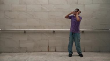 Yakışıklı hippi dans ederken müzik dinler ya da dans ederken dans eder. Çekici bir sokak dansçısı B-boy ayak sesleri çıkarıyor. Serbest dans konsepti. Yaşam tarzı. Açık hava sporu 2024. Yumuşak bir şekilde..