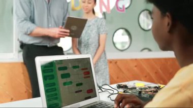 Beyaz kız tableti sorup işaret ederken Afrikalı erkek programlama sistemi. Akıllı öğretmen, Stem dersinde kodlama sorusuna cevap verirken tableti elinde tutuyor. Öğretim