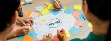 Profesyonel başlangıç grubu zihin haritası kullanarak yaratıcı pazarlama fikrini paylaşıyor. Genç yetenekli iş adamları yapışkan notlar yazarken beyin fırtınası planı yapıyorlar. Eline odaklan. - Yakın çekim. Değiştirilmiş.