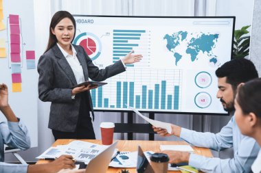 Genç Asyalı iş kadını modern toplantıda TV ekranında veri analizi paneli sunuyor. Bir grup iş adamıyla konferans odasında iş sunumu. Uyum