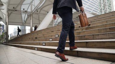 Şehir manzarasıyla çevrili merdivenlerden çıkan işadamlarının bacakları. Hırslı proje yöneticisinin modern inşaatta zorlu bir iş ya da yatırım fırsatı bulması. Urbane.