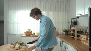 Mutlu baba yemek pişirirken müziğe geçiyor ve modern mutfakta öğle yemeği hazırlıyor. Aktif baba, sebze ve mutfak gereçleri ile çevrili sağlıklı yemek ya da salata yaparken şarkıyla dans ediyor. Pedagoji.