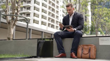 Kafkas iş adamları yeşil şehirde otururken tablet üzerinde çalışıyorlar. Uzman yönetici iş ekibiyle çalışırken finansal veri analizi yapmak ve aramak için tablet kullanıyor. Urbane.