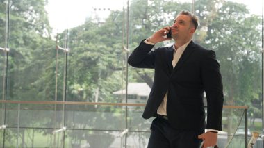 Kafkas işadamı akıllı telefon kullanarak müdürü arıyor ve mali raporları tartışıyor. Erkek lider, modern binada merdivenlerde dururken telefonla pazarlama ekibini konuşuyor. Urbane.