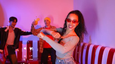 Çok kültürlü bir arkadaş birlikte dans ediyor ve hiphop müziği eşliğinde restoranda ya da kafede pembe neon ışıklı duruyor. Profesyonel sokak dansçıları grubu enerjik hareketler sergiliyor. Mutluluk.