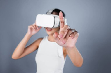 Gri arka planı olan zeki bir kadın metaevrene bağlı VR kulaklık takıyor, gelecekçi siber uzay topluluğu teknolojisi. Zarif bir kadın sanal bir manzara gördüğü için heyecanlı. Halüsinasyon.