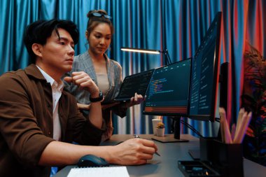 Modern ofisteki neon ışık odasında bilgi ağını gösteren dizüstü bilgisayarla iki ekranda veri çalıştıran akıllı web sitesi geliştirme kodlayıcı sistemini tartışan IT geliştiricilerinin ciddiyeti. İnfobahn.