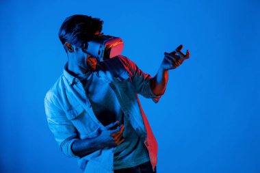 Beyaz adam hareket ediyor, gitar çalıyor ve arka planda ışık yansıması olan bir VR cam takıyor. Oyuncu metaevren ya da sanal gerçeklik programına teknolojik yenilikler kullanarak girer. Sapma.