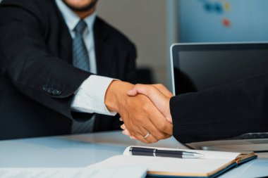 İş adamları konsepti kabul ediyor. İş adamı ve Asyalı iş kadını ofiste el sıkışırlar. uds