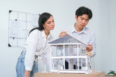 Kooperatif mühendis ekibinin portresi ev modelini ölçmek için cetvel ve mimari ekipmanlar kullanarak birlikte çalışıyor. Yaratıcı iş tasarımı ve takım çalışması konsepti. Tertemiz...