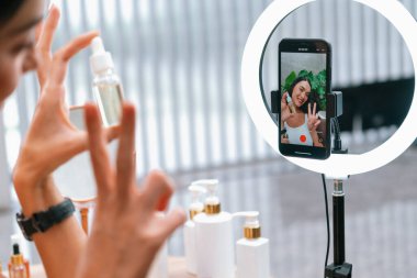 Sosyal medya için güzellik ve kozmetik video içeriği hazırlayan genç bir kadın. Güzellik blogcusu seyirciye güzellik hizmetini nasıl uygulayacağını ya da kamera karşısında takipçiyi nasıl izleyeceğini gösteriyor. Blithe