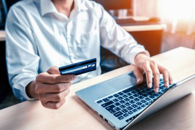Genç adam, laptop bilgisayar başvurusu ya da web sitesinde online alışveriş yapmak için kredi kartı kullanıyor. E-ticaret ve online alışveriş konsepti. uds