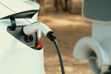 Kapalı EV şarj kolu fişe takıldı veya elektrikli arabaya bağlandı, EV araba aküsünü temiz çevre için sıfır CO2 emisyonu ile alternatif ve sürdürülebilir enerjiyle şarj etti. Kalıcı