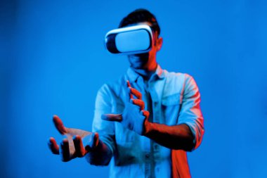 Beyaz, zeki bir adam, sanal gerçeklik gözlüğü kullanırken hareketli hareketler yapıyor. Sanal dünyaya girerken kulaklık ve gözlük kullanan ya da neon ışıklı arka plan ile metaevrene giren mutlu insan. Teknoloji. Sapma.