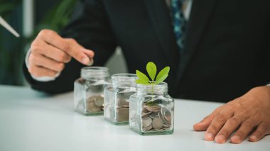 İşadamı, sürdürülebilir para büyümesi yatırımı veya eko-sübvansiyon olarak ofisindeki cam kavanozdan tasarruf edilen paraya para koydu. Yeşil kurumsal promosyon ve çevre bilincine yatırım. Döngü