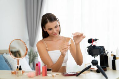 Sosyal medya için güzellik ve kozmetik video içeriği hazırlayan genç bir kadın. Güzellik blogcusu kameraya gülümserken seyircilere ve takipçilere güzellik bakımını gösteriyor. Açılıyor