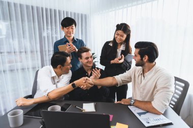 Çeşitli ofis çalışanları stratejik iş pazarlama toplantısı üzerine anlaşma yaptıktan sonra el sıkışıyor. Takım çalışması ve olumlu tutum verimli ve destekleyici bir iş yeri yaratır. Tedbirli