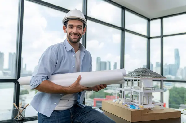 stock image Portrait of professional architect engineer thinking about modern house project while wearing safety helmet and casual outfit. Smart interior designer holding project plans near house model. Tracery.
