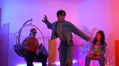 Çok kültürlü bir arkadaş kürsüde otururken Asyalı yetenekli bir dansçı modern müziğe geçiyor. Profesyonel dansçı, hipster takımı tezahürat yaparken ve desteklerken enerjik adımlar atıyor. Mutluluk.