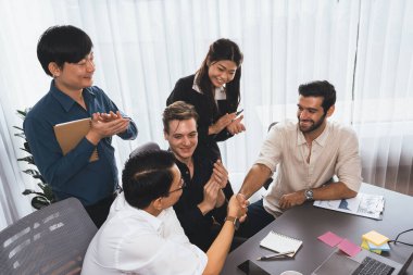 Çeşitli ofis çalışanları stratejik iş pazarlama toplantısı üzerine anlaşma yaptıktan sonra el sıkışıyor. Takım çalışması ve olumlu tutum verimli ve destekleyici bir iş yeri yaratır. Tedbirli