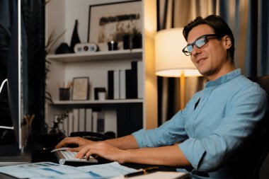 Akıllı iş adamı iş paragrafı dinamik pazarlama analizi planını analiz ediyor. Kağıt kağıtları ve bilgisayar monitörü raporlarını gece evdeki belge verileriyle karşılaştırmak için hazırlıyor. Bireysel.