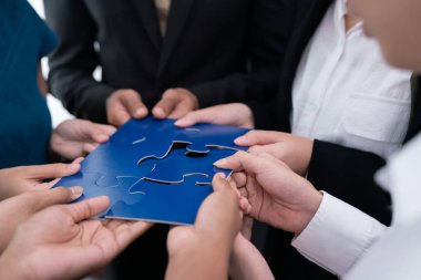 Çeşitli şirket çalışanları, ortaklık ve takım çalışmasını temsil etmek için bulmaca parçalarını birleştirerek ofiste işbirliği yapıyor. Yapboz 'u birleştirerek iş dünyasındaki birlik ve sinerji. Uyum