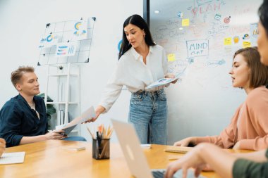 Güzel, genç, beyaz bir lider, modern iş toplantı odasında grafik ve zihin haritası kullanarak iş pazarlama stratejisi hakkında sunum yaparken, erkek yatırımcılara toplantı belgeleri veriyor. Tertemiz..