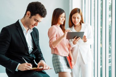 Kitap okuyan ve iş yerinde iş arkadaşları ve arkadaşlarıyla çalışan genç ve yakışıklı bir işadamı. Kurumsal iş adamları grubu. uds