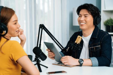 Gülümseyen radyo etkili sunucu elinde tablet, kulaklık takıyor kadın konuşmacı sosyal medya online canlı yayın kanalı ile röportaj yapıyor ve sabah stüdyo kaydında paylaşım linkini paylaşıyor. İnfobahn.