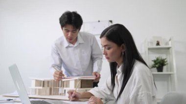 Happy, mimari belge ve ev modeli ile toplantı masasında dizüstü bilgisayar analiz verilerini kullanarak birlikte çalışan profesyonel mimar takımı ile işbirliği yapıyor. Yaratıcı tasarım konsepti. Tertemiz..
