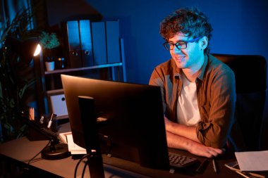 Neon Light Modern Ofis 'te yaratıcı bir başlangıç projesi için bilgisayara odaklanan gülümseyen genç iş adamı. Düşünüyorum da, pazarlama ağı yaratıcıdan pazar kanalı tasarım konseptine çevrimiçi planlama. Toplayıcı.