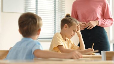 Beyaz bir çocuk ödevlerini yaparken ve açıklama dinlerken güzel bir öğretmen sınavı açıklıyor. Sınıfta not alırken ya da kağıda cevap yazarken öğretmenine bakan sevimli bir çocuk. Pedagoji.