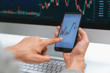 Akıllı borsa yatırımcıları ekranda akıllı telefon ile piyasa borsasını işaret ederek dizüstü bilgisayarın yanı sıra en yüksek dinamik yatırım oranını göstererek, modern işyerindeki veri planlamasına odaklanıyorlar. Bireysel.