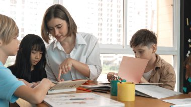 Çizim kitabında işaret kullanarak çeşitli öğrencilerin ve zeki öğretmen çizimleri ve boyamaları mutlu olsun. Çok kültürlü, zeki bir öğrenci yetenekli beyaz bir eğitmenle konuşurken çizim kitabı kullanıyor. Etkinlik.